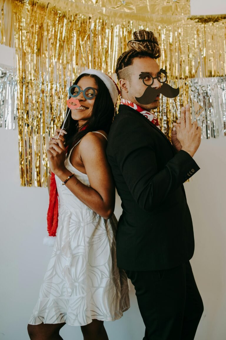 A joyful couple in costumes celebrating at a festive indoor holiday party.